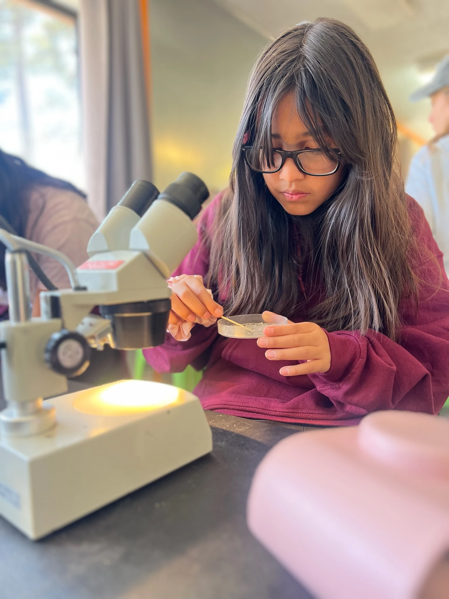 Page Academy student examining a sample under a microscope at AstroCamp