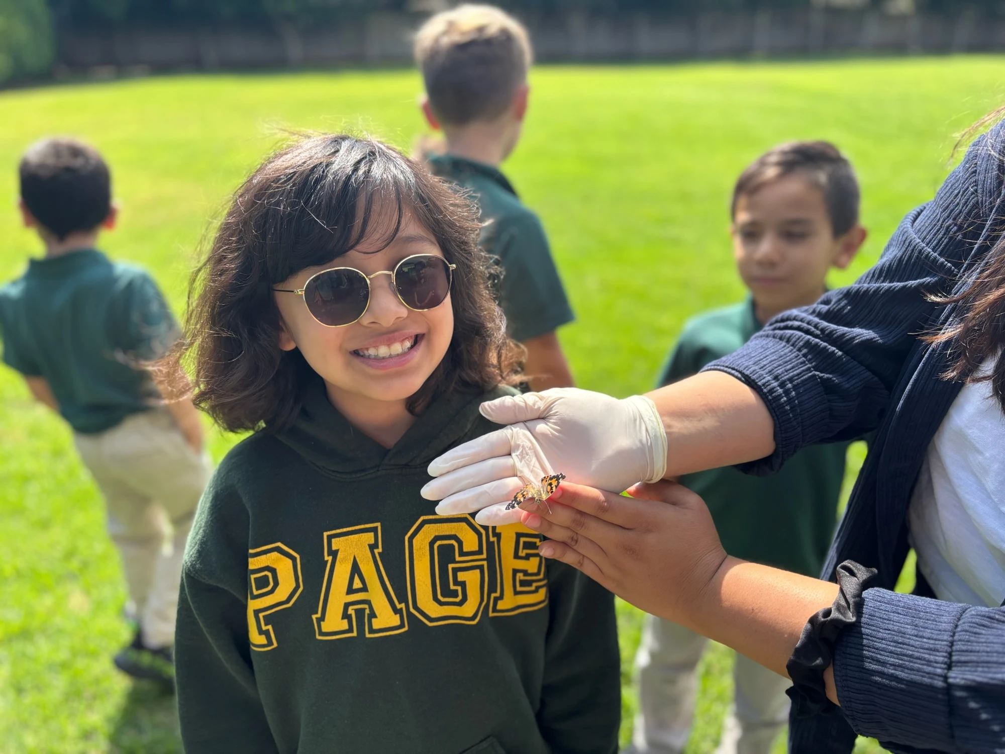 Page Academy student smiling on the field in a Page hoodie